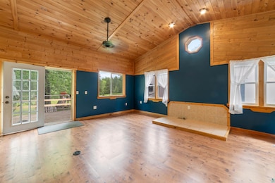 Unfurnished living room with wood ceiling, lofted ceiling, wooden walls, and wood finished floors