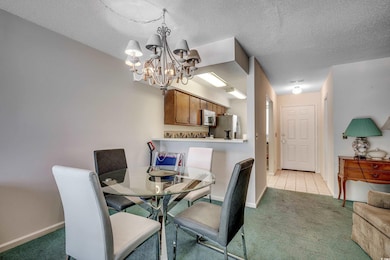Dining area featuring light carpet, a chandelier, baseboards, a textured ceiling, and light tile patterned floors
