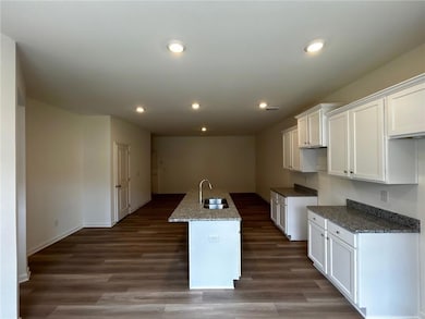 Kitchen featuring white cabinetry, a kitchen island with sink, dark stone countertops, dark wood-type flooring, and recessed lighting