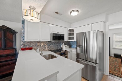 Kitchen featuring white cabinetry, a textured ceil