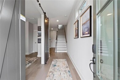 Entryway featuring recessed lighting, light wood-type flooring, baseboards, a barn door, and stairs