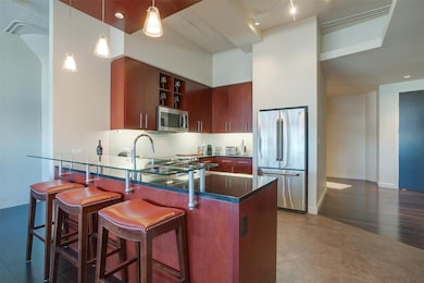 #2452 stainless steel finishes, a peninsula, decorative light fixtures, tasteful backsplash, and rail lighting