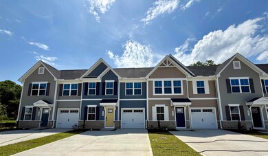 Multi unit property with driveway, stone siding, a garage, and board and batten siding