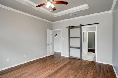 Empty room featuring a barn door, a ceiling fan, 