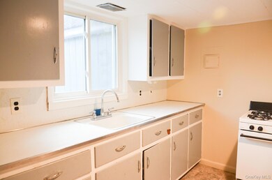 Kitchen with white range with gas stovetop, light countertops, and white cabinets
