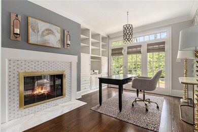 Multi purpose space featuring crown molding, built in shelves, dark wood-style flooring, and a tile fireplace
