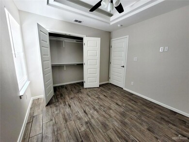 Unfurnished bedroom featuring dark wood-style flooring, a raised ceiling, a closet, and ceiling fan