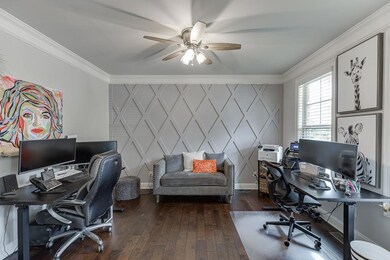 Office space with a decorative wall, crown molding, a ceiling fan, and hardwood / wood-style floors