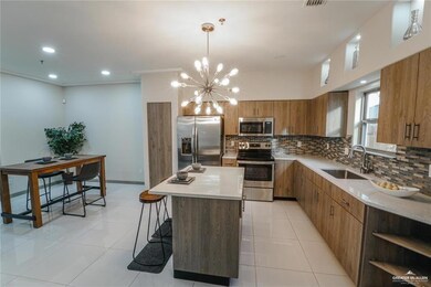 Kitchen featuring stainless steel appliances, a kitchen island, tasteful backsplash, a sink, and brown cabinetry