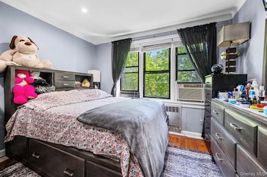 Bedroom with dark wood-style floors, cooling unit, and radiator heating unit