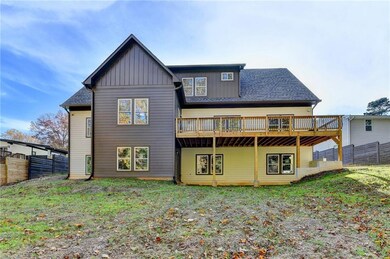 Rear view of property with a deck, board and batten siding, and roof with shingles