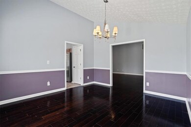 Unfurnished dining area featuring a chandelier, baseboards, a textured ceiling, wood finished floors, and high vaulted ceiling
