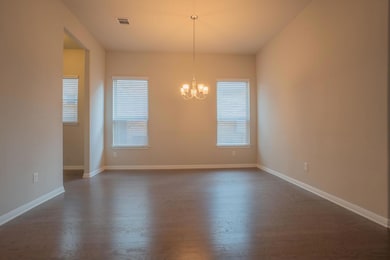 Unfurnished dining area with plenty of natural light, dark wood-style floors, and a chandelier