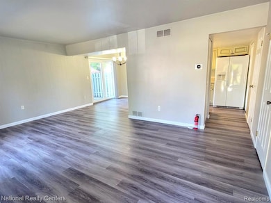 Empty room featuring dark wood-type flooring and a chandelier