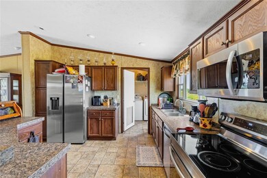 Kitchen with stainless steel appliances, a sink, crown molding, stone tile floors, and independent washer and dryer