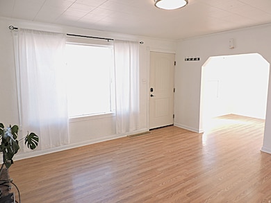 Foyer entrance with light wood-type flooring, arched walkways
