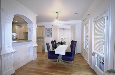 Dining space featuring arched walkways, light wood-type flooring, decorative columns, a chandelier, and ornamental molding