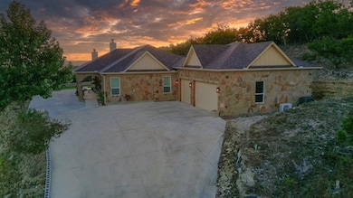 View of front of home featuring a garage, stone siding and driveway