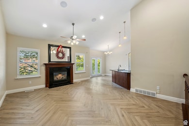 Unfurnished living room featuring a ceiling fan, a fireplace with flush hearth, a chandelier, recessed lighting, and high vaulted ceiling