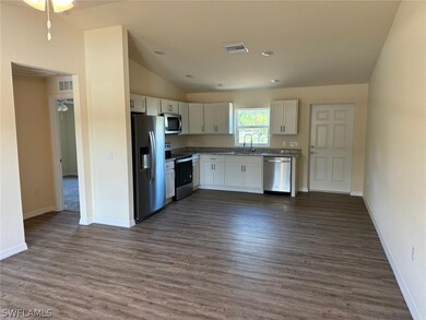 Kitchen with dark hardwood / wood-style flooring, white cabinets, lofted ceiling, and stainless steel appliances