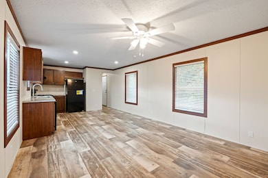 Open concept living area (924 sq. ft. total) flowing into the kitchen with a ceiling fan and LED can lights throughout