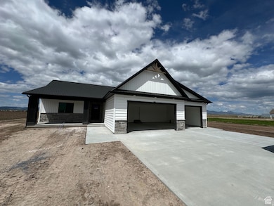 Modern farmhouse featuring stone siding, driveway, and a garage