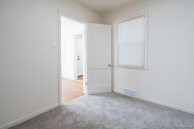 Carpeted spare room featuring baseboards