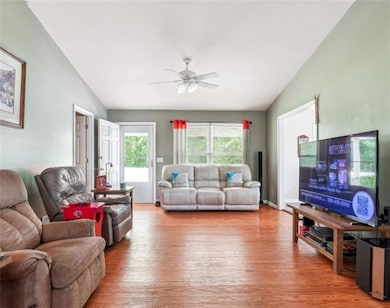 Living area with lofted ceiling, wood finished floors, and a ceiling fan