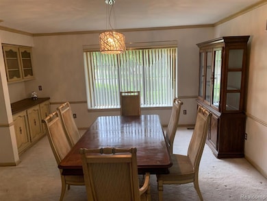 Dining room with ornamental molding, light carpet, and a chandelier
