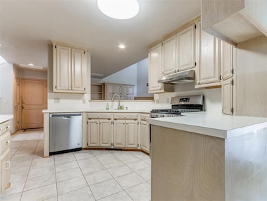 Kitchen with appliances with stainless steel finishes, under cabinet range hood, light countertops, a sink, and recessed lighting