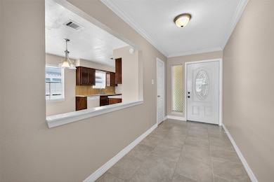 This photo shows a welcoming
entryway with tiled flooring and neutral
walls, leading to an open view of the
kitchen. The kitchen features dark wood
cabinets, a window for natural light, and
a decorative light fixture. The entry door
has a decorative glass panel, adding
charm to the space.