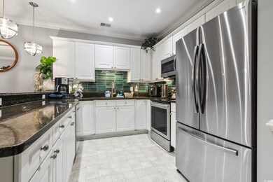 Kitchen featuring white cabinetry, appliances with stainless steel finishes, crown molding, and pendant lighting
