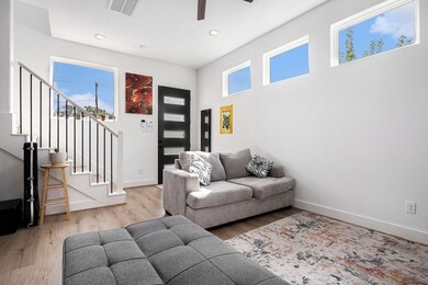 This bright, modern living room, large windows for natural light. The space includes a stylish black-accented staircase.