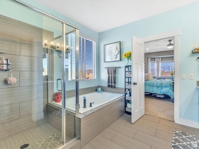 Ensuite bathroom featuring a stall shower, a garden tub, wood tiled floors, and vanity