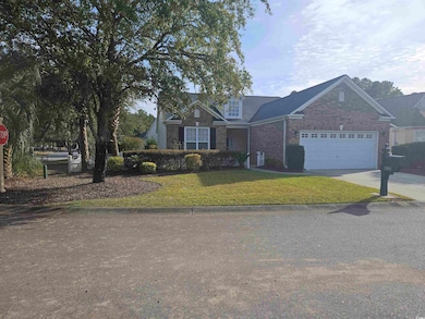 View of front of house with a front yard, driveway, brick siding, and a garage