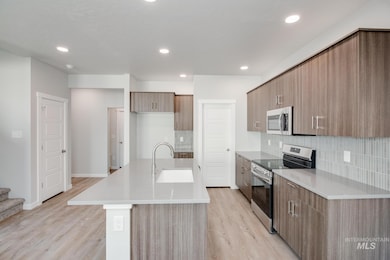 Kitchen with stainless steel appliances, light wood-type flooring, decorative backsplash, light countertops, and recessed lighting