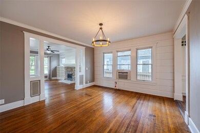 Dining room with ornamental molding, a fireplace, ceiling fan with notable chandelier, and dark wood-type flooring