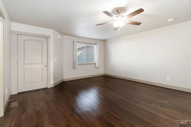 Unfurnished room featuring dark wood-type flooring and a ceiling fan