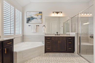 Full bathroom with a garden tub, vanity, a shower stall, and lofted ceiling