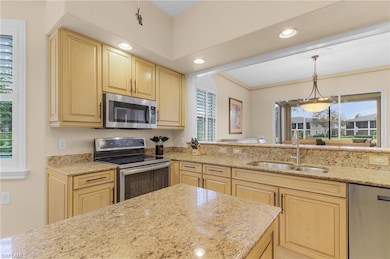 Kitchen featuring stainless steel appliances, recessed lighting, decorative light fixtures, light brown cabinets, and light stone counters