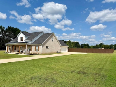 View of front facade featuring a porch, brick siding, concrete driveway, a garage, and roof with shingles