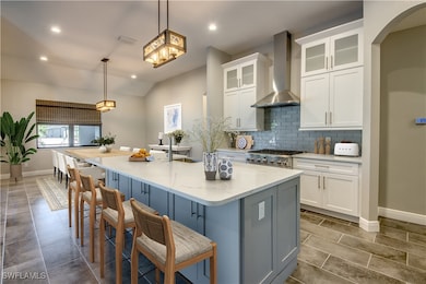Virtually Staged Kitchen with visible vents, backsplash, white cabinetry, and wall chimney range hood