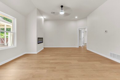 Empty room with a ceiling fan, a glass covered fireplace, light wood-style floors, baseboards, and recessed lighting