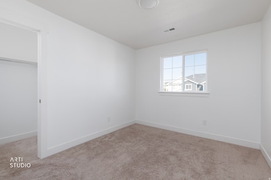 Unfurnished bedroom with light carpet and a walk in closet