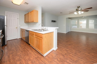 Kitchen featuring light brown cabinetry, light countertops, open floor plan, a ceiling fan, and a textured ceiling
