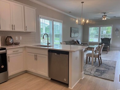 Kitchen featuring appliances with stainless steel finishes, a sink, light countertops, open floor plan, and ornamental molding