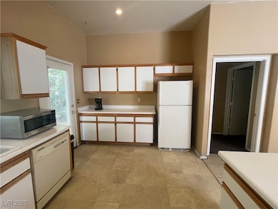 Kitchen featuring white appliances, light countert