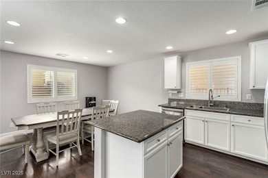Kitchen with dark wood-type flooring, dark stone c