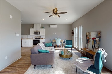 Living area with ceiling fan, baseboards, a wall u
