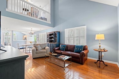 Living area with light wood-style flooring, a towering ceiling, and a chandelier
